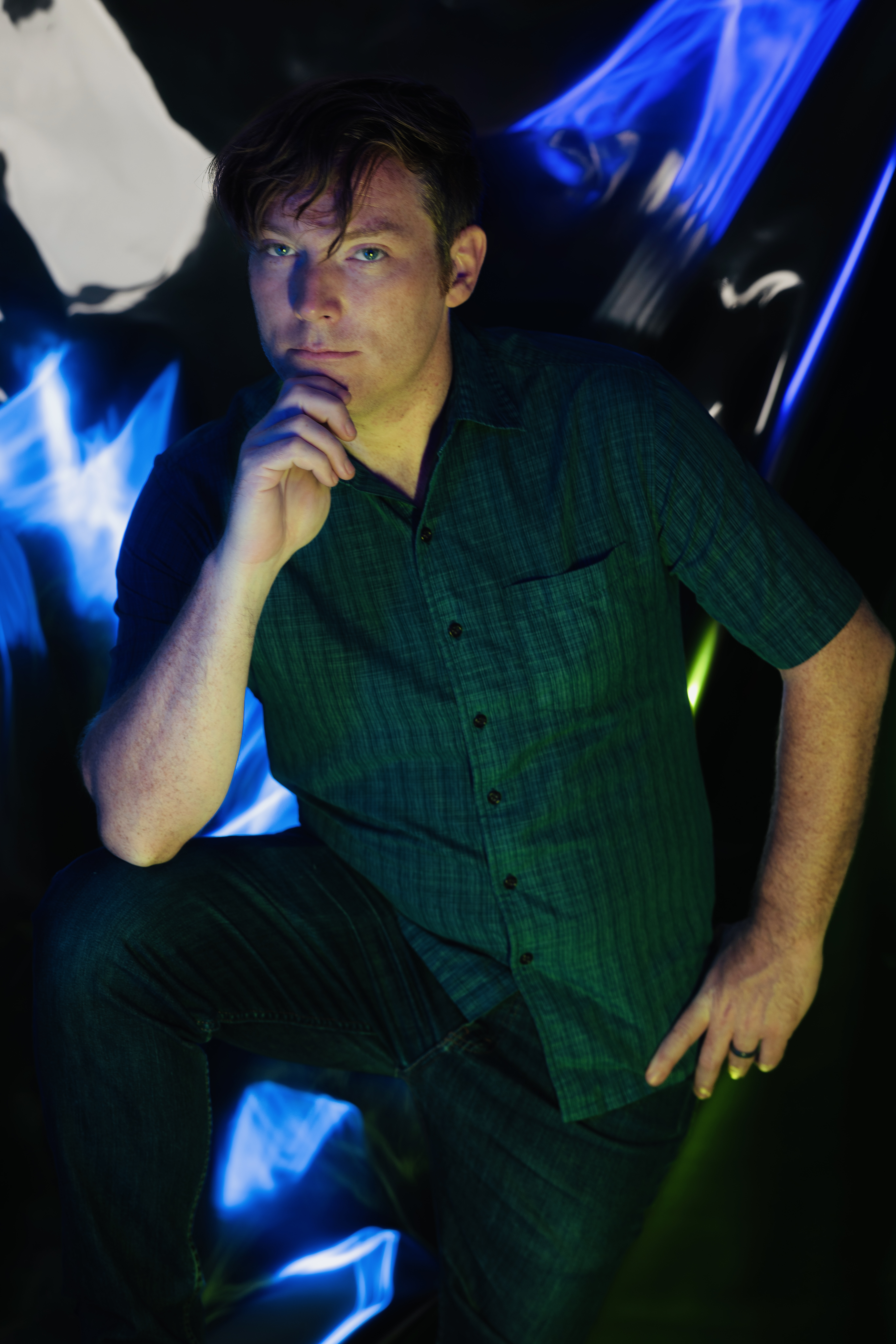 Ryan Griswold looks at the camera while standing in front of a colorful background