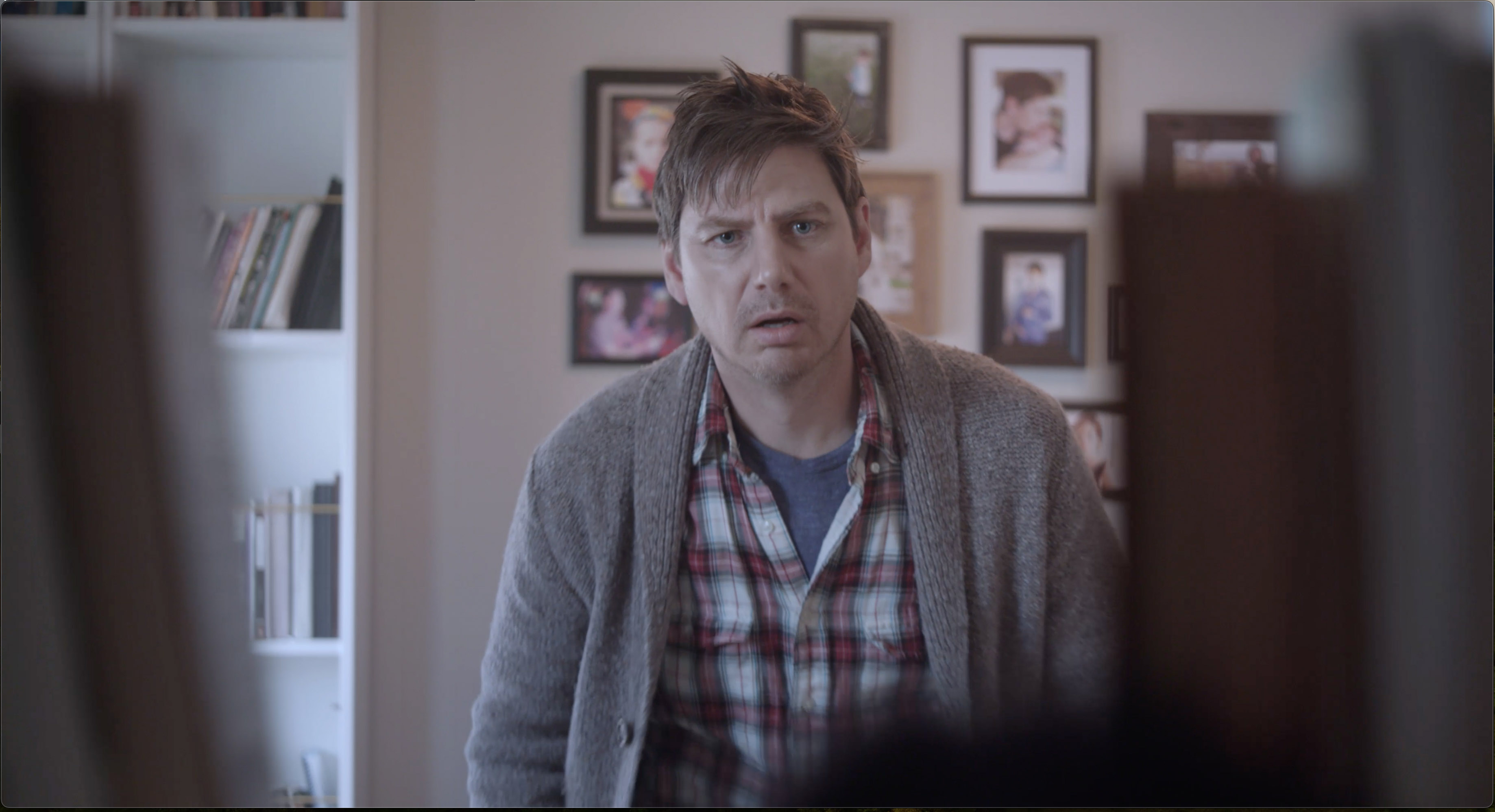 A man in plaid shirt stares dumbfounded at the camera